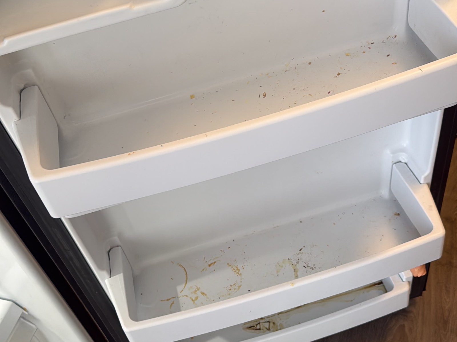 Refrigerator door shelves with grime before cleaning